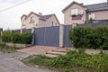 Part of a private house behind a fence with a gate in green vegetation Royalty Free Stock Photo