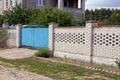 Part of a private house behind a fence with a gate in green vegetation Royalty Free Stock Photo