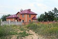 Part of a private house behind a fence with a gate in green vegetation Royalty Free Stock Photo