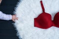 Part of red bodice and little child`s hand on white fur. Underwear, fashion working concept. Close up