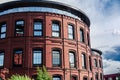 Part of red brick corporate building with sky reflections in the windows against sky with grey clouds background Royalty Free Stock Photo