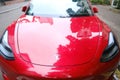 part of red electric car parked on street, popular sedan from company Elon Musk, alternative energy development concept, clean