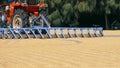 Red tractor is working on grain paddy rice drying courtyard inside of rice mill area Royalty Free Stock Photo