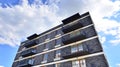 Part of a residential building  with balconies and blue sky with clouds. Royalty Free Stock Photo