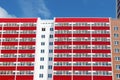 Part of residential building with many red loggias at sunny