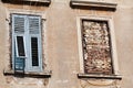Part of residential building with old windows wooden shutters and window is walled up, closeup / Building facade elements. Royalty Free Stock Photo
