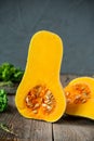 Part of ripe orange pumkin with seeds stading on the rustic wooden table on the dark grey stone background. Vegetarian, healthy di
