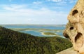 Part of the rock against the backdrop of a forested mountain slope and a panorama of a blue lake and clouds Royalty Free Stock Photo
