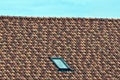 Part of the roof with a colored tiled surface and a small window on the sky background Royalty Free Stock Photo