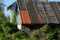 Part of the roof of an old rural house in a thicket of plants Royalty Free Stock Photo