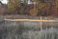 Part of a rural fence made of brown wooden planks in gray dry grass Royalty Free Stock Photo