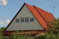Part of a rural house from the attic with a window under the red slate against the sky