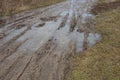 Part of a rural road made of gray dirt and potholes with puddles