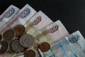 Part of Russian paper money and a scattering of metal coins of different denominations on them close-up on a black background Royalty Free Stock Photo