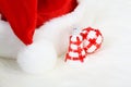 Part of Santa Claus hat with pom-pom and red and white Christmas ball and Christmas smaller bell on white fur Royalty Free Stock Photo