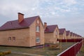 Part of the street with typical two-story red brick houses. New condominium or village. Blue sky with copy space. Affordable Royalty Free Stock Photo