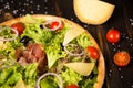 Part of Traditional Italian pizza with jamon Serrano, salad mix, cheese, black olives and cherry tomatoes. Royalty Free Stock Photo