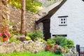 Part of a traditional white English style cottage with stone wall, garden and potted flowers. Cute vintage exterior. Outdoor Royalty Free Stock Photo