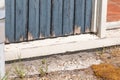 Part of an unmaintained door and frame. Paint is peeling off, rotten frame. Deferred maintenance. Brick wall