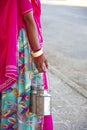 Part view of a woman's hand with many bracelets, carrying two milk churns