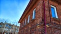 Part of wall made of the red brick, windows and fragment of roof of modern private dwelling house against of sky