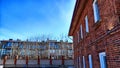 Part of wall made of the red brick, windows and fragment of roof of modern private dwelling house against of sky