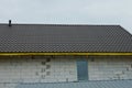 Part of a white brick house with a window under a brown tiled roof Royalty Free Stock Photo