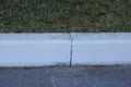 Part of a white concrete curb on a gray asphalt