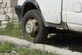 Part of a white minibus with one black dirty wheel stands on the ground