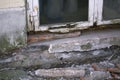 Part of the white wooden frame of an old window with peeling paint and rotten wood and plaster on facade crumbles due to moisture