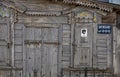 Part of the wooden facade of an old dilapidated house with carved platbands, curly wall elements and metal bars with a Beware of Royalty Free Stock Photo