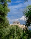 Parthenon on acropolis hill between green folliage, Athens Greece