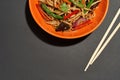 Partial of asian noodles in bowl and chopsticks