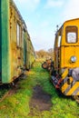 Partial and front view of old yellow ruined train control cabin and passenger carriage Royalty Free Stock Photo