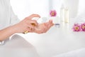 partial image of woman using aroma oil at table with towels, flowers and candles