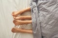 Partial of legs of girls under blanket on bed