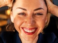 Partial portrait of a girl with strong white teeth looking at the camera and smiling, fingers near her face.