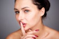 Partial portrait of mysterious woman with finger pressed to lips