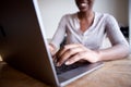 Partial portrait of smiling woman sitting at desk and typing on laptop computer