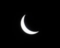 Partial solar eclipse with moon blocking sun, sun shining in a crescent shape in black sky Royalty Free Stock Photo
