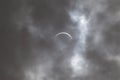 Partial solar eclipse - moon covers sun, dark clouds, celestial drama - crescent sun - atmospheric mood Royalty Free Stock Photo