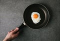 partial top view of person holding frying pan with fried egg on grey Royalty Free Stock Photo