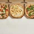 Partial top view of three variety pizzas in boxes