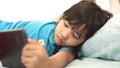 Partial view of Asian little girl using tablet in bed at home, mobile gadget addiction on children Royalty Free Stock Photo