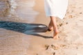 partial view of barefoot girl in white dress walking on sandy beach Royalty Free Stock Photo