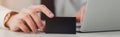 partial view of businessman holding empty black business card while using laptop in office, panoramic shot. Royalty Free Stock Photo