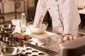 partial view of confectioner standing at counter with raw dough
