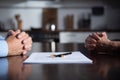 View of couple sitting at table with clenched hands near divorce documents