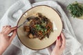 partial view of female hands and soba with tofu and vegetables decorated with germinated seeds of sunflower