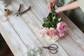 Partial view of the florist making a bouquet of flowers in a light workshop on a wooden surface. Royalty Free Stock Photo